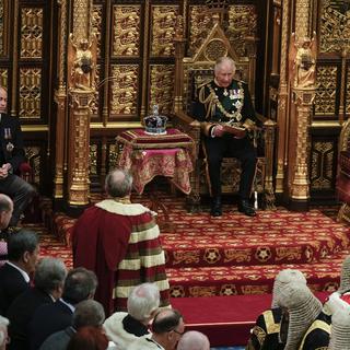 Charles prend la place d'Elizabeth II pour le traditionnel discours devant le Parlement, avec William à sa droite et Camilla à sa gauche. [Keystone - AP Photo/Alastair Grant, Pool]