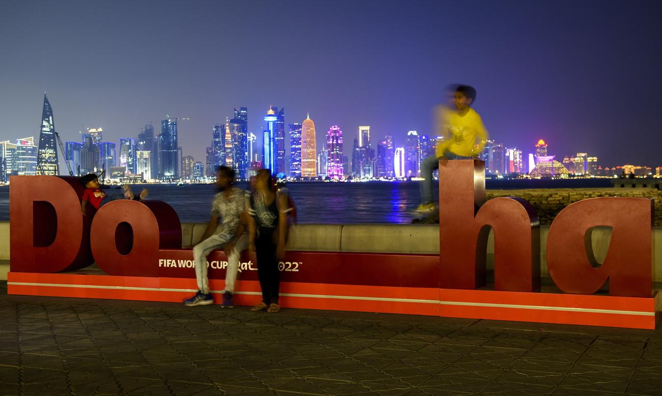 Des personnes posent devant la signalétique du Mondial de football au Qatar, le 20 octobre à Doha. [EPA/Keystone - Noushad Thekkayil]