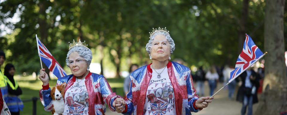 Des fans royaux portant des masques de la Reine Elizabeth se préparent à la cérémonie de la parade du jubilé de platine de la Reine Elizabeth à Londres, Grande-Bretagne, le 2 juin 2022. [EPA/KEYSTONE - Tolga Akmen]