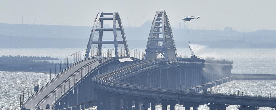 Un hélicoptère largue de l'eau pour éteindre l'incendie sur le pont entre la Crimée et la Russie. [Keystone/AP Photo]