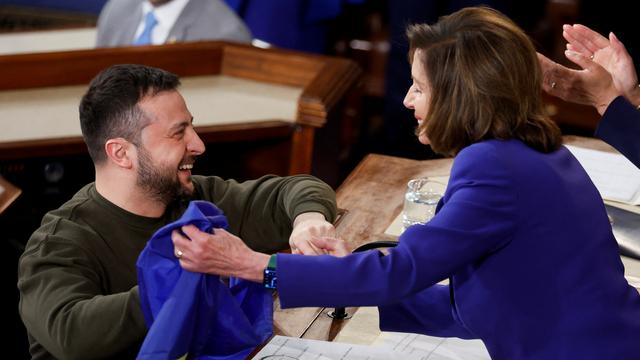 Le président ukrainien Volodymyr Zelensky présente un drapeau ukrainien qui lui a été donné par les défenseurs de Bakhmut à la présidente de la Chambre des États-Unis Nancy Pelosi lors d'une réunion conjointe du Congrès américain. [reuters - Jonathan Ernst]