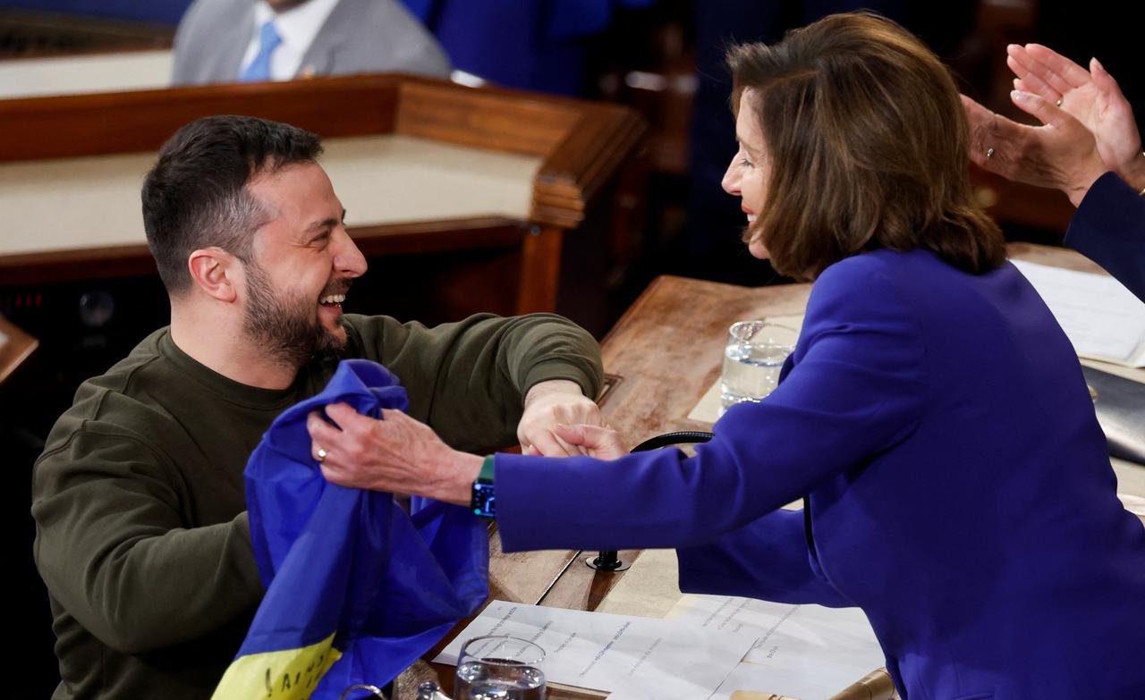 Le président ukrainien Volodymyr Zelensky présente un drapeau ukrainien qui lui a été donné par les défenseurs de Bakhmut à la présidente de la Chambre des États-Unis Nancy Pelosi lors d'une réunion conjointe du Congrès américain. [reuters - Jonathan Ernst]