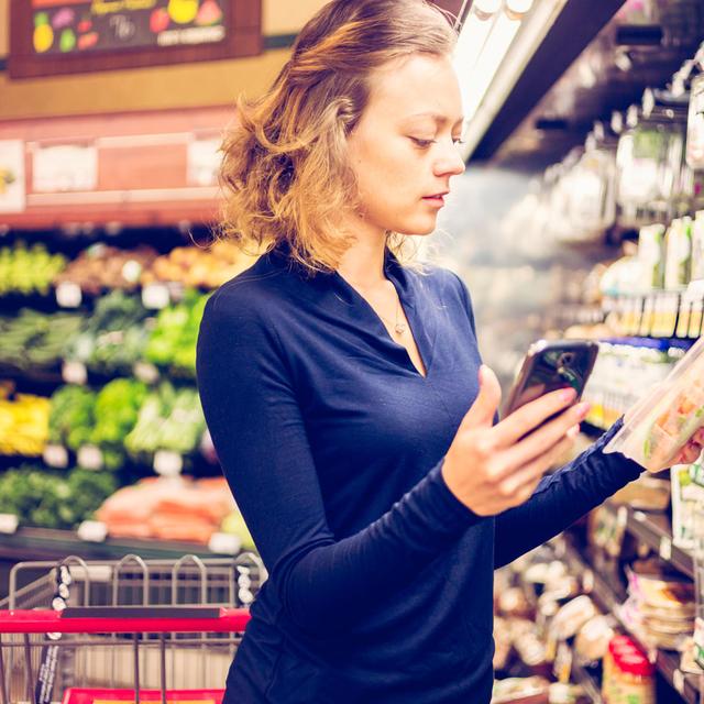 Une femme scanne un produit avec son smartphone dans un supermarché. [Depositphotos - urban_light]