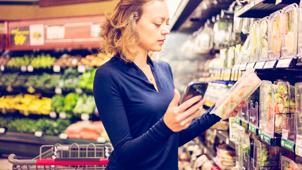 Une femme scanne un produit avec son smartphone dans un supermarché. [Depositphotos - urban_light]