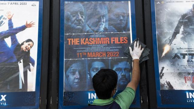 Un ouvrier nettoie un présentoir avec l’affiche du film The Kashmir Files devant un cinéma à New Delhi. [Xavier Galiana]