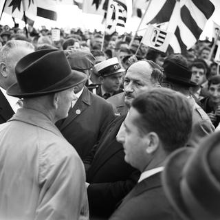 Le conseiller fédéral Paul Chaudet, au centre, semble gêné après que son discours ait été noyé par les cris de protestation des séparatistes jurassiques, le 30 août 1964. 
PHOTOPRESS-ARCHIVE/ai
KEYSTONE [KEYSTONE - PHOTOPRESS-ARCHIVE/ai]