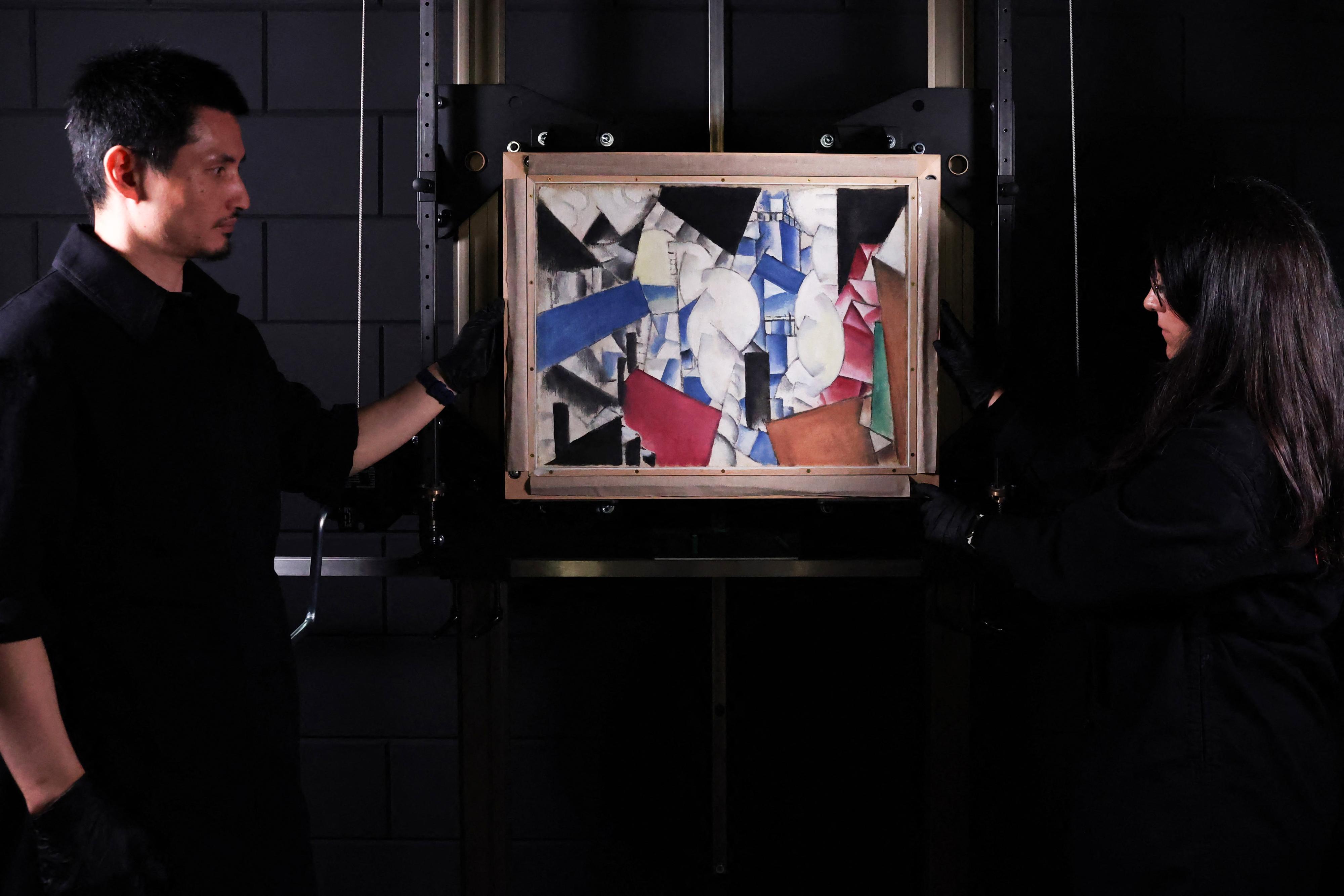 Des experts en art dévoilent la toile de Fernand Léger "Fumée sur les toits" explosée au Studio Redivivus, situé à La Haye [AFP - FRANÇOIS WALSCHAERTS]