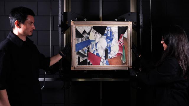 Des experts en art dévoilent la toile de Fernand Léger "Fumée sur les toits" explosée au Studio Redivivus, situé à La Haye [AFP - FRANÇOIS WALSCHAERTS]