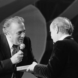 Le cinéaste Federico Fellini remet un prix au compositeur Nino Rota lors du gala du Midem à Cannes, le 13 janvier 1975. [AFP - GEORGES GALMICHE / Ina]