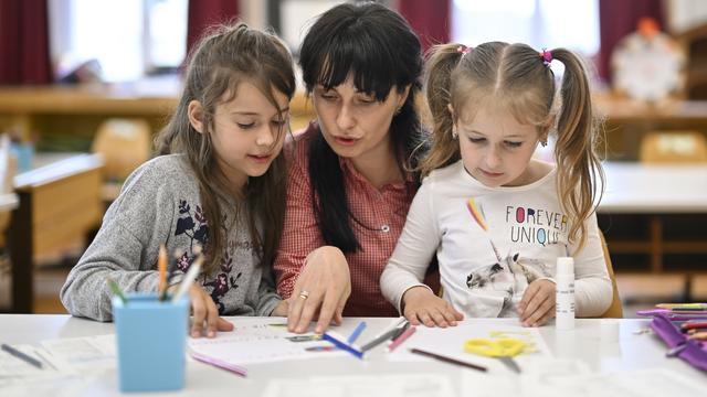 Deux enfants réfugiées d'Ukraine et leur enseignante à Herisau, en Appenzell, le 13 mai 2022. [Keystone - Gian Ehrenzeller]