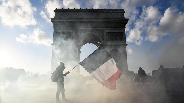 Un manifestant agite le drapeau français devant l'Arc de triomphe à Paris en marge d'une manifestation des gilets jaunes le 16 mars 2019. [AFP - Alain Jocard]