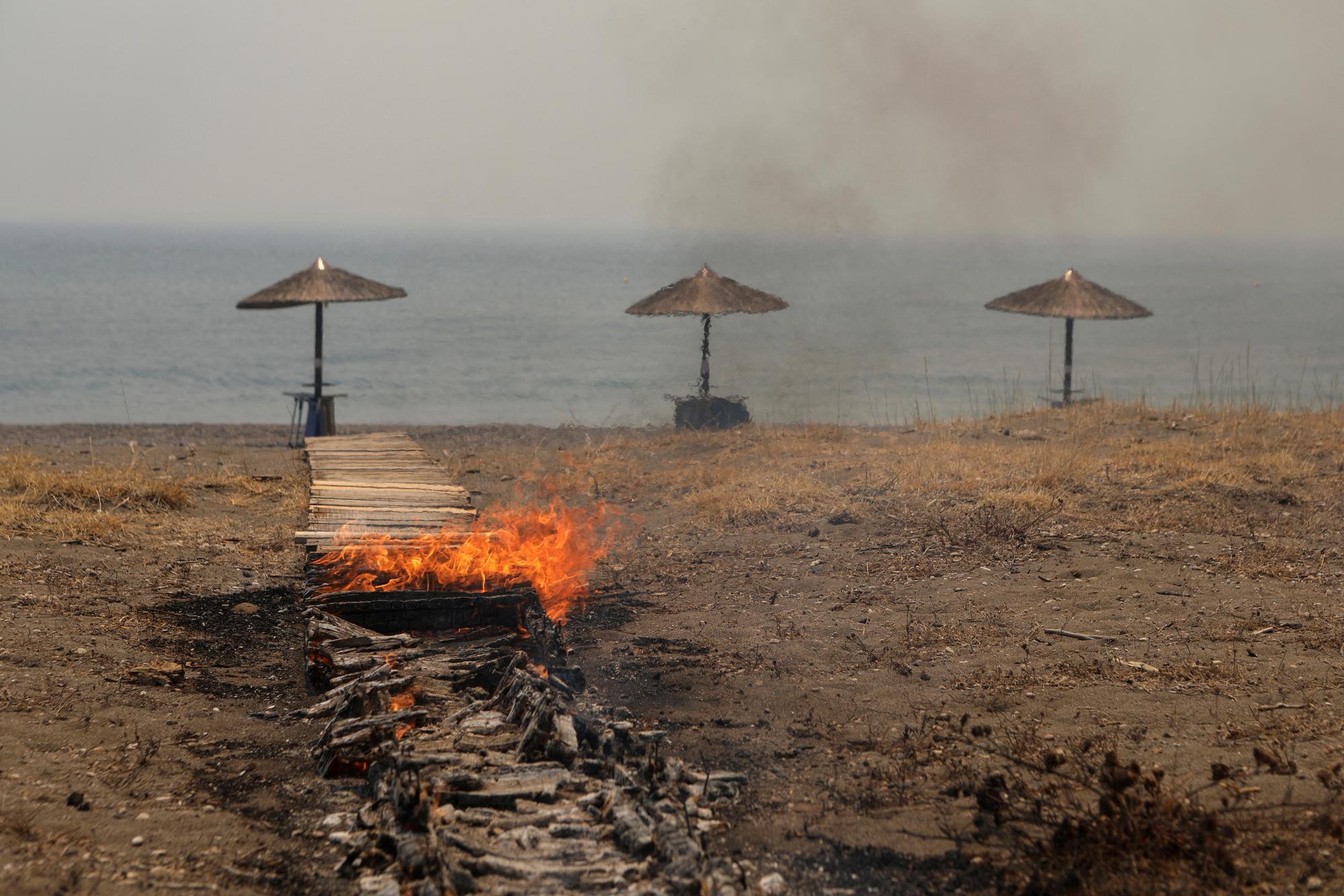 Un bar de plage en feu sur l'île de Lesbos. [Reuters - Elias Marcou]