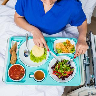 Une femme mange de la nourriture servie en hôpital. [Depositphotos - Romaset]