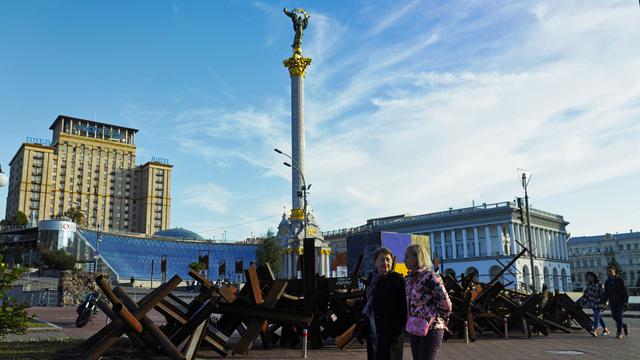 Des personnes se baladent à côté du monument de l'Indépendance (Kiev). [Keystone/ AP photo - Jon Gambrell]