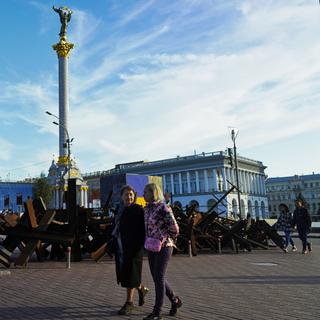 Des personnes se baladent à côté du monument de l'Indépendance (Kiev). [Keystone/ AP photo - Jon Gambrell]