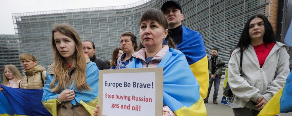 Des Ukrainiens manifestent devant les institutions européennes à Bruxelles pour demander de nouvelles sanctions. [Keystone/EPA - Olivier Hoslet]