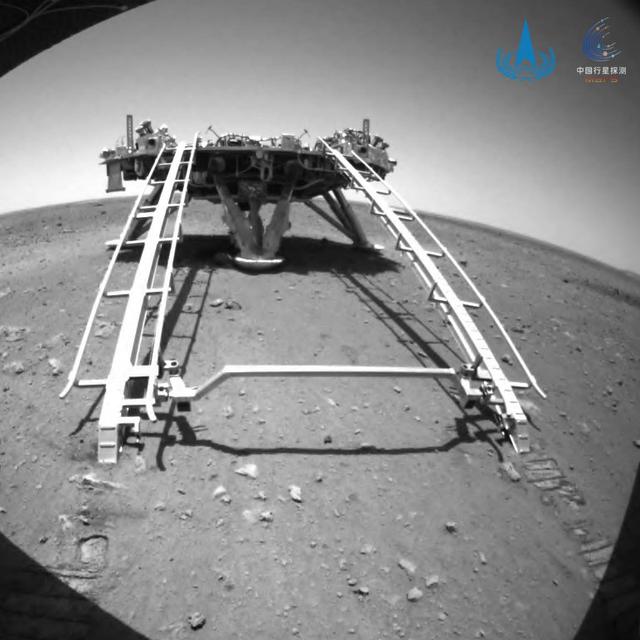 Sur cette photo publiée le 23 mai 2021 par l'Administration spatiale nationale chinoise (CNSA), le rover chinois Zhurong, de la mission Tianwen-1, descend de sa plate-forme d'atterrissage sur la surface de Mars. Il s'agissait là de sa sa première sortie sur la surface de la planète rouge. [EPA / China National Space Administration]