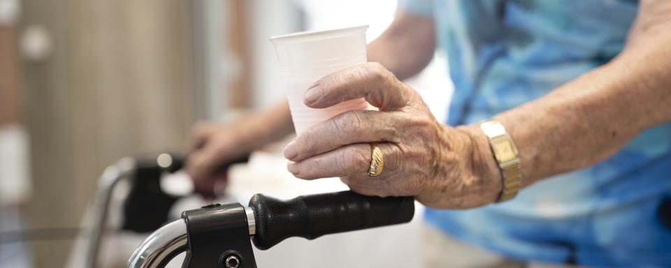 Une résidente du centre d’âge Herzogenmuehle avec une tasse de thé froid à la main, le 8 juillet 2019 à Zurich. [Keystone - Gaetan Bally]