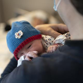 Un père tient sans ses bras sa fille qui vient de naître. [Keystone - Gaëtan Bally]