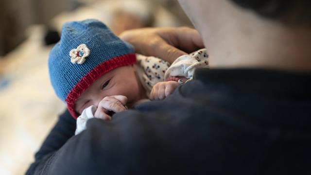 Un père tient sans ses bras sa fille qui vient de naître. [Keystone - Gaëtan Bally]