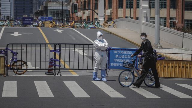 Un homme passe devant un officier de police à Shanghai, en Chine, le 9 mai 2022. [EPA/Keystone - Alex Plavevski]