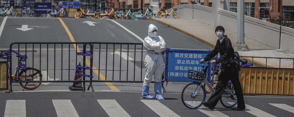 Un homme passe devant un officier de police à Shanghai, en Chine, le 9 mai 2022. [EPA/Keystone - Alex Plavevski]