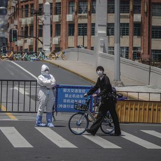 Un homme passe devant un officier de police à Shanghai, en Chine, le 9 mai 2022. [EPA/Keystone - Alex Plavevski]