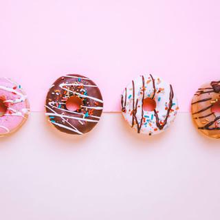 Quatre donuts décorés disposés sur fonds colorés. [Unsplash - Najla Cam]