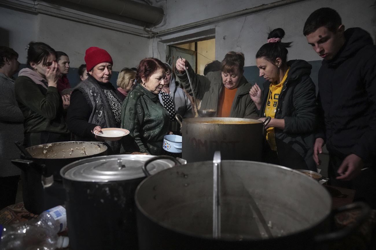 Des habitants et habitantes de Marioupol font la queue pour un bol de soupe, dans un abri anti-atomique à Marioupol, en Ukraine, le 7 mars 2022. [AP/Keystone - Evgeniy Maloletka]