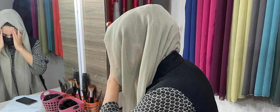 La journaliste de la chaîne de télévision afghane TOLOnews, Tahmina Osmani, se prépare à mettre un hijab avant de prendre l'antenne devant les caméras. [RTS - Raphaël Grand]