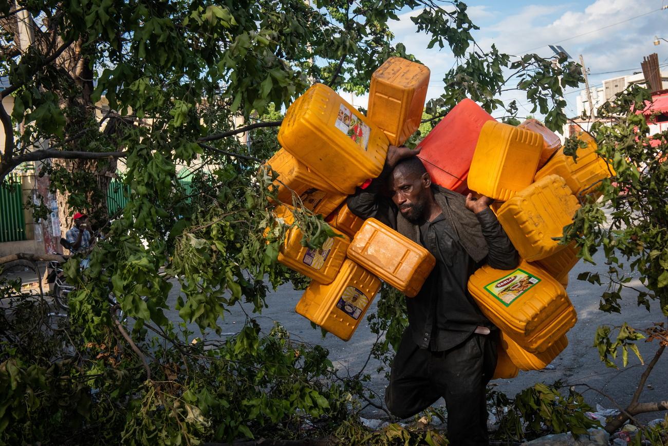 Un homme porte des jerricans dans l'espoir de stocker de l'essence, à Port-au-Prince en Haïti où une pénurie de carburant fait rage. [EPA/Keystone - Johnson Sabin]