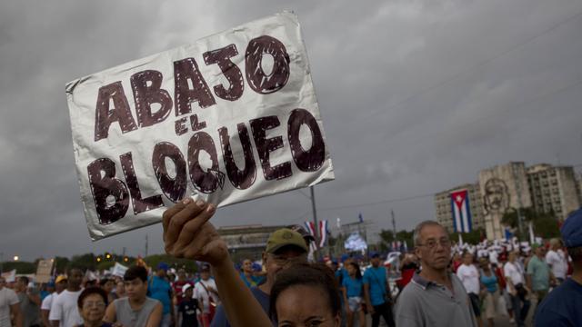 Une femme brandit une pancarte écrite à la main contre l'embargo américain lors d'une marche sur la place de la Révolution marquant le 1er mai, à La Havane, Cuba, vendredi 1er mai 2015. [AP Photo/KEYSTONE - Ramon Espinosa]