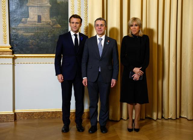 Le président de la Confédération Ignazio Cassis, entre Emmanuel et Brigitte Macron, lors du Forum de la Paix à Paris, le 11 novembre 2022. [EPA/Keystone - Gonzalo Fuentes]