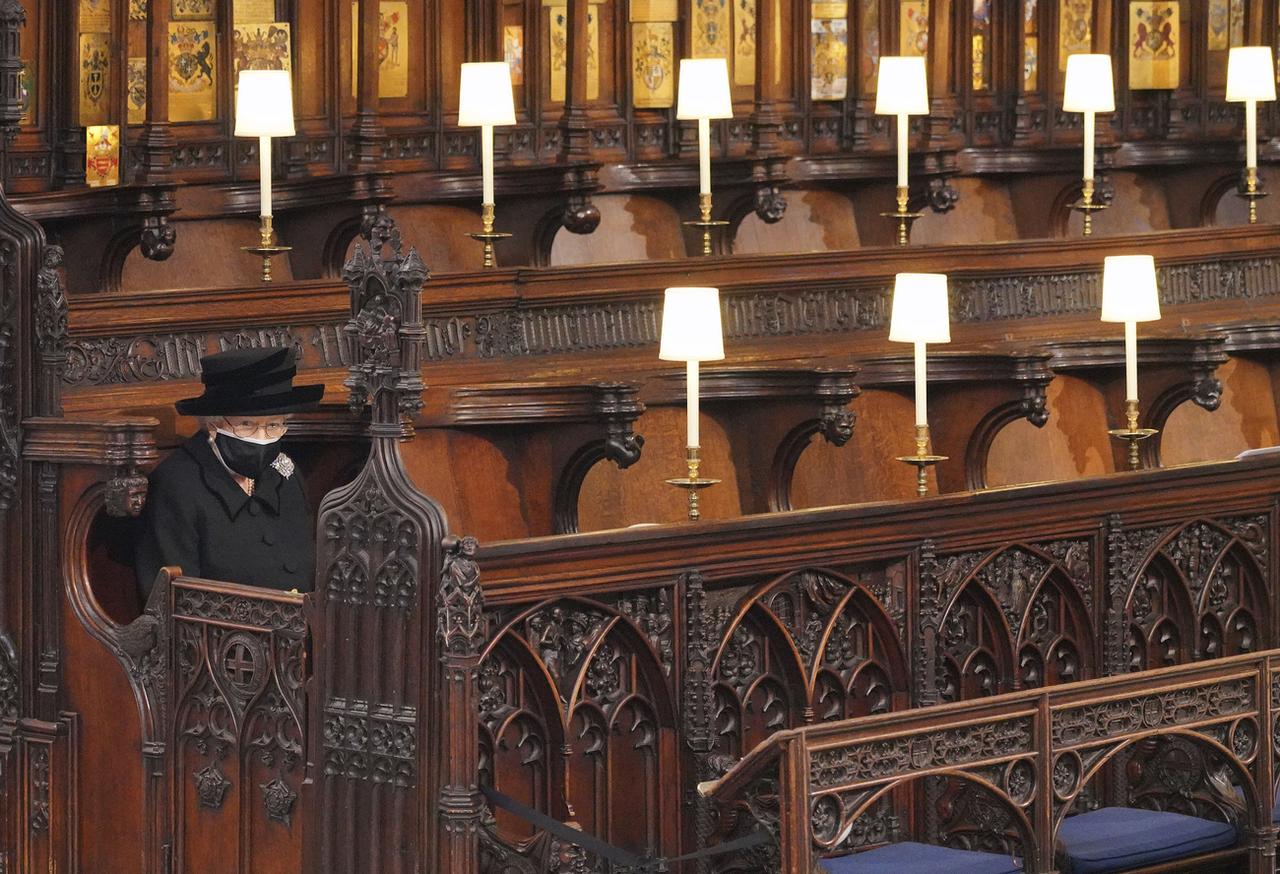 La reine assise seule dans la chapelle St George de Windsor lors des funérailles du Prince Philip, en pleine pandémie de coronavirus, le 17 avril 2021. [Keystone - Jonathan Brady]