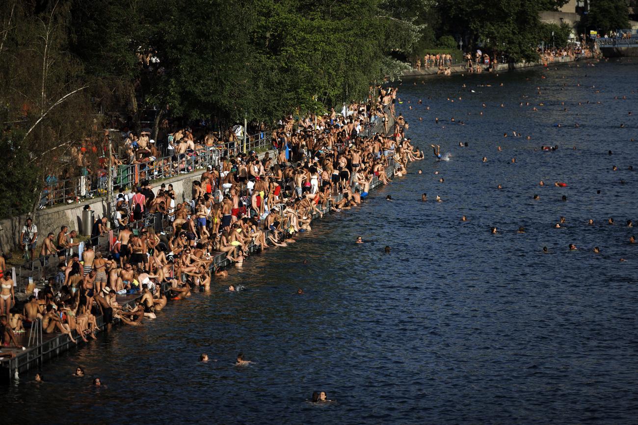 Des personnes se baignent dans la rivière Limmat, à Zurich, samedi 18 juin 2022, alors qu'une vague de chaleur atteint le pays en Suisse. [KEYSTONE - Michael Buholzer]