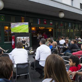 Des supporters de football regardent un match du Mondial 2014 dans un bar. [Keystone - Jean-Christophe Bott]