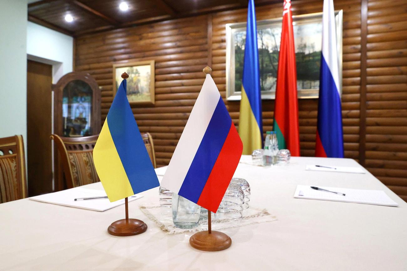 Les drapeaux ukrainiens et russes lors d'un round de négociations entre les deux belligérants. [Keystone/EPA - Maxim Guchek]