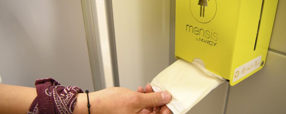 Une jeune fille d'une classe de 9e année secondaire utilise une serviette hygiénique gratuite provenant d'un distributeur dans les toilettes de l'école. [KEYSTONE - Laurent Gillieron]