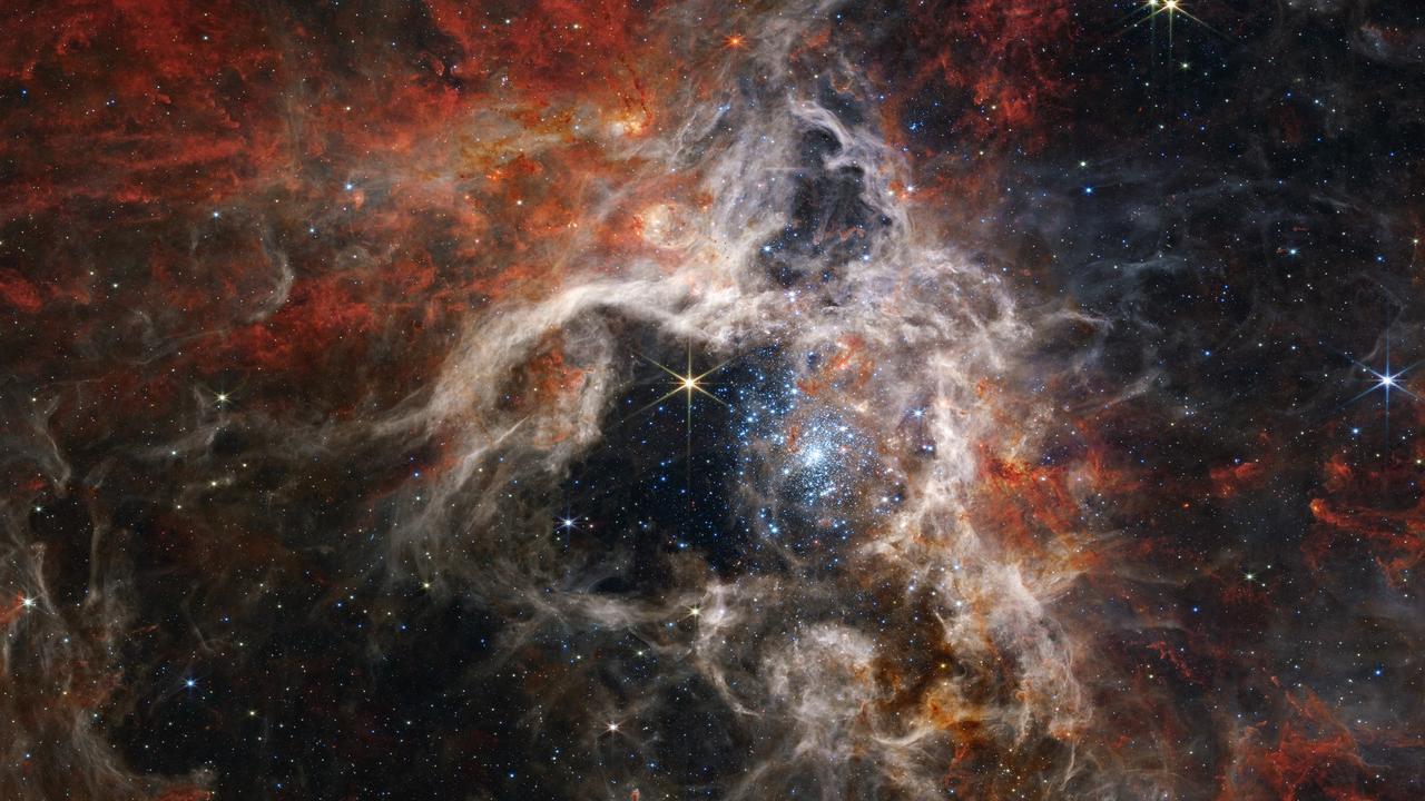 Dans cette image mosaïque s'étendant sur 340 années-lumière, la caméra en infrarouge proche de Webb (NIRCam) révèle la région de formation d'étoiles de la nébuleuse de la Tarentule sous un nouveau jour, avec des dizaines de milliers de jeunes étoiles jamais vues auparavant: elles étaient jusqu'ici enveloppées de poussière cosmique. [NASA, ESA, CSA, STScI - Webb ERO Production Team]
