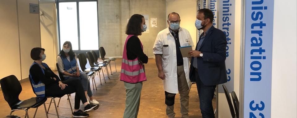 Le centre de consultation du canton de Fribourg, avec Raphaëlle Henry, responsable du centre médical d'appui à l'asile, le docteur Eric Devaud et le médecin cantonal adjoint Christophe Monney. En chasuble bleue, des interprètes pour les patients ukrainiens. [RTS - Muriel Ballaman]