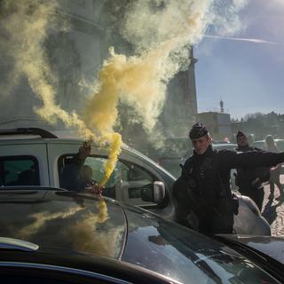 Des participant au "convoi de la liberté" font usage de fumigène sur la Place de l'Etoile près de l'Arc de Triomphe à Paris. [Keystone/EPA - Christophe Petit Tesson]