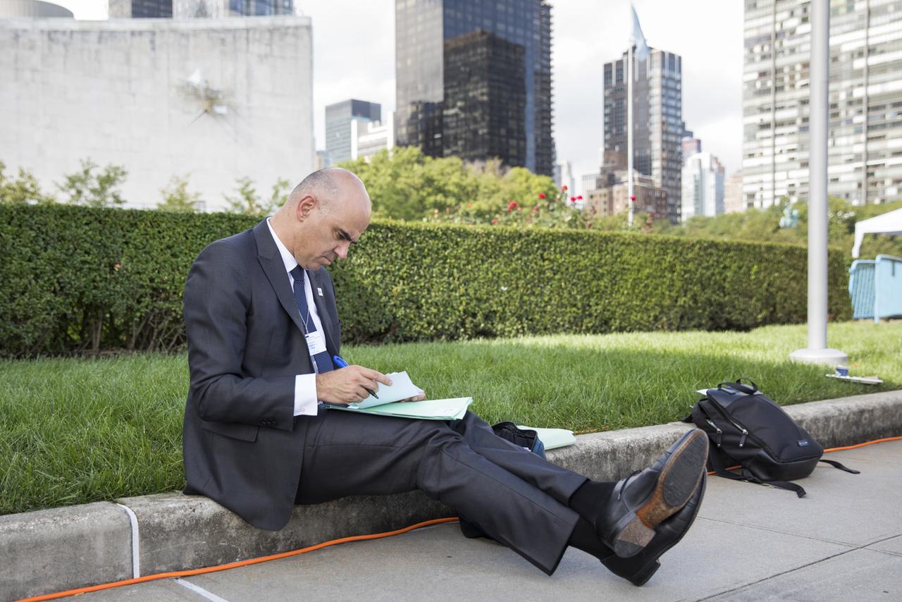 Alain Berset, alors président de la Confédération, prenant des notes assis par terre en marge de la 73e session de l'Assemblée générale de l'ONU le 26 septembre 2018. [Keystone - Peter Klaunzer]