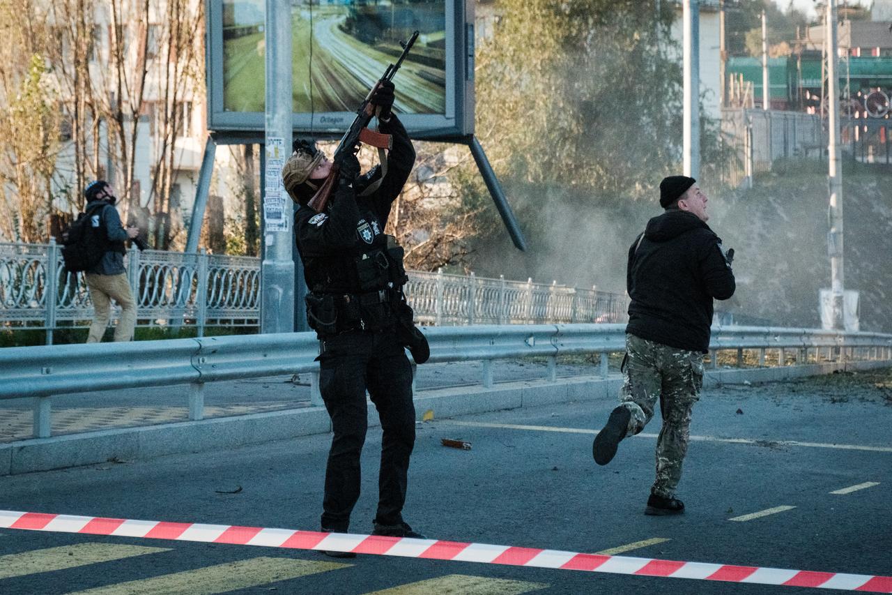 Un policier ukrainien tente d'abattre un drone kamikaze avec sa kalashnikov à Kiev, le 17 octobre 2022. [AFP - Yasuyoshi CHIBA]