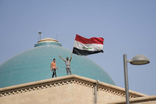 Des partisans de Moqtada Sadr sur le toit du palais de la République. [Keystone/AP - Hadi Mizban]