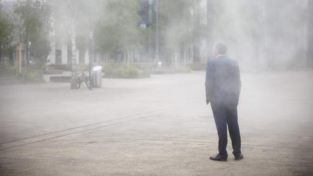 Un homme se refroidit sous le nouveau nuage de brouillard sur la Turbinenplatz, à Zurich [Keystone - Michael Buholzer]