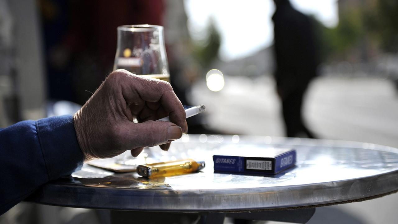 Un homme fumant une cigarette sur une terrasse. [Keystone - Dominic Favre]