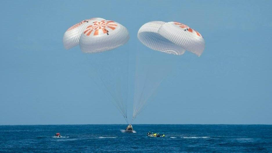 La descente de la capsule a été freinée par son entrée dans l'atmosphère, puis par d'immenses parachutes. [Handout / SPACEX / AFP]