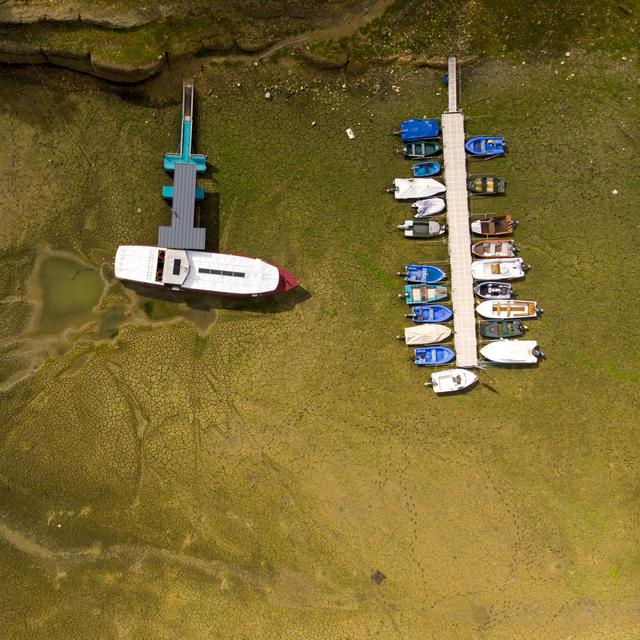 Des bateaux échoués dans la boue sur la rive asséchée du Lac des Brenets sur le Doubs, le 17 août 2022. L'Europe lutte contre les pénuries d'eau alors qu'une grave sécheresse sévit sur le continent. [KEYSTONE - Laurent Gillieron]