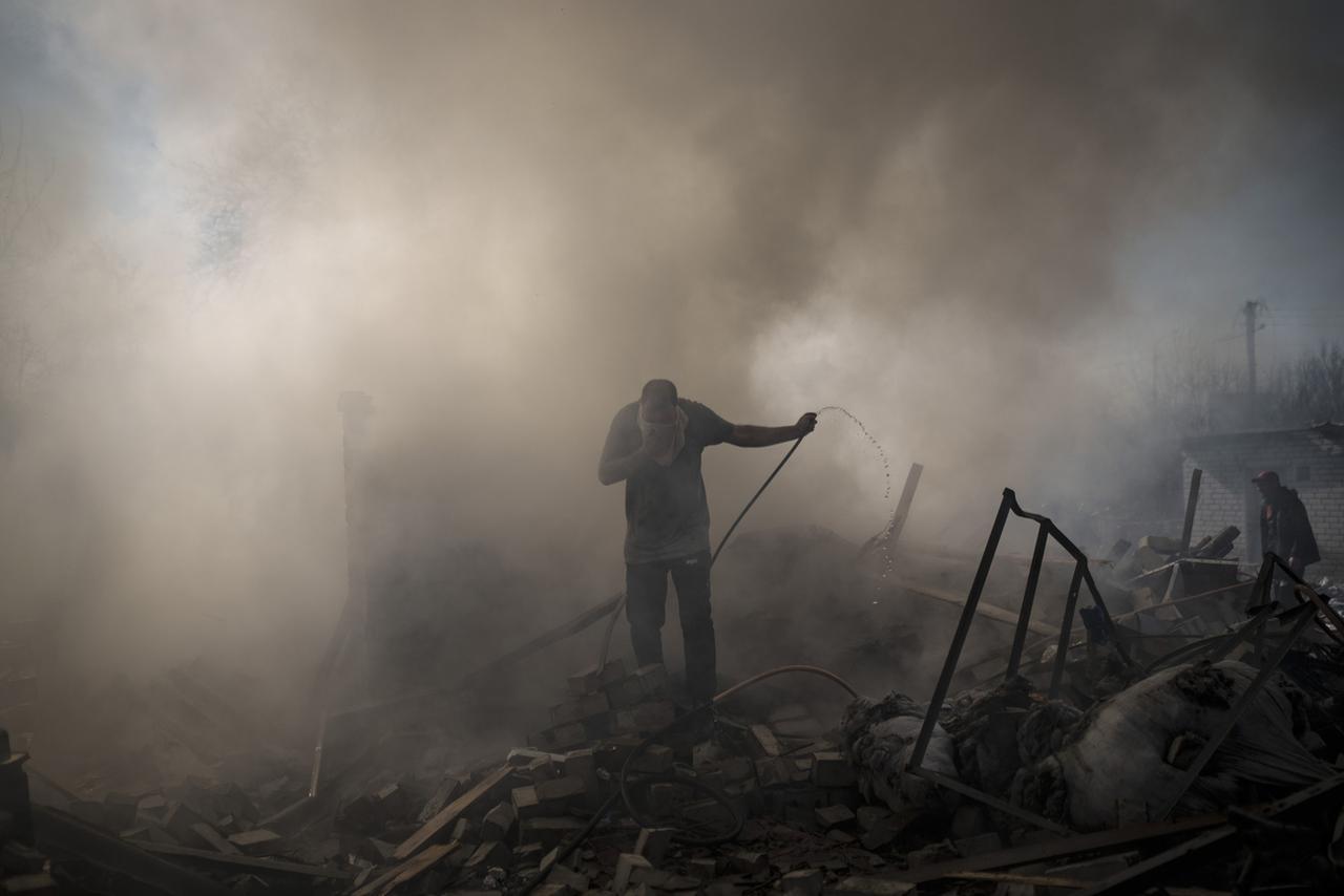 Des habitants tentent d'éteindre l'incendie après un bombardement de l'armée russe à Kharkiv, en Ukraine, le 24 mars 2022. [Keystone - Felipe Dana]