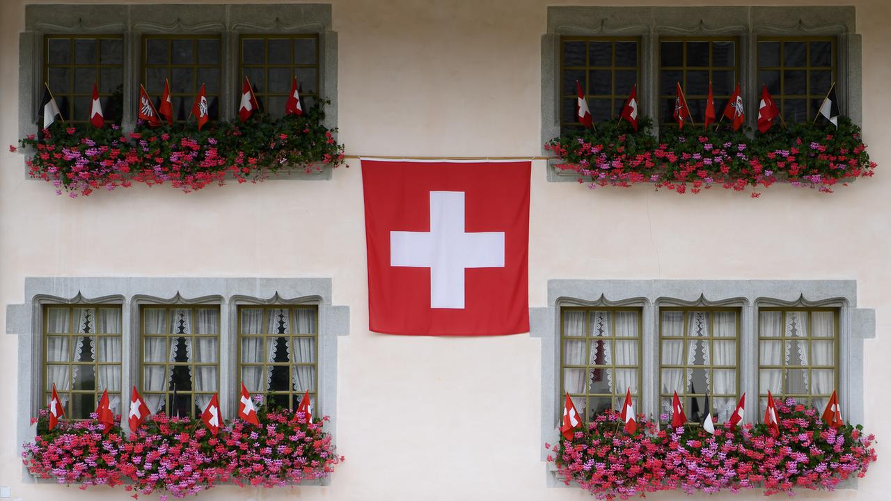 Un drapeau suisse est photographié sur la façade d'un bâtiment lors des festivités du 1er août, à Gruyères. [KEYSTONE - Anthony Anex]